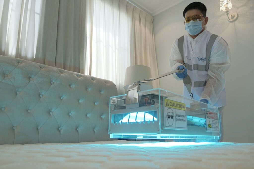 pexels photo 14675104 Technician sanitizing hotel room bed with UV light for safe and clean environment.